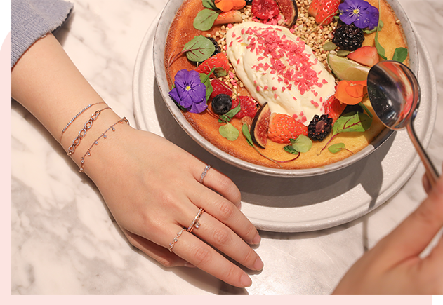 Close-up of a woman's hand adorned with a bracelet and ring, enjoying a beautifully plated dessert, promoting the mori Loyalty Programme